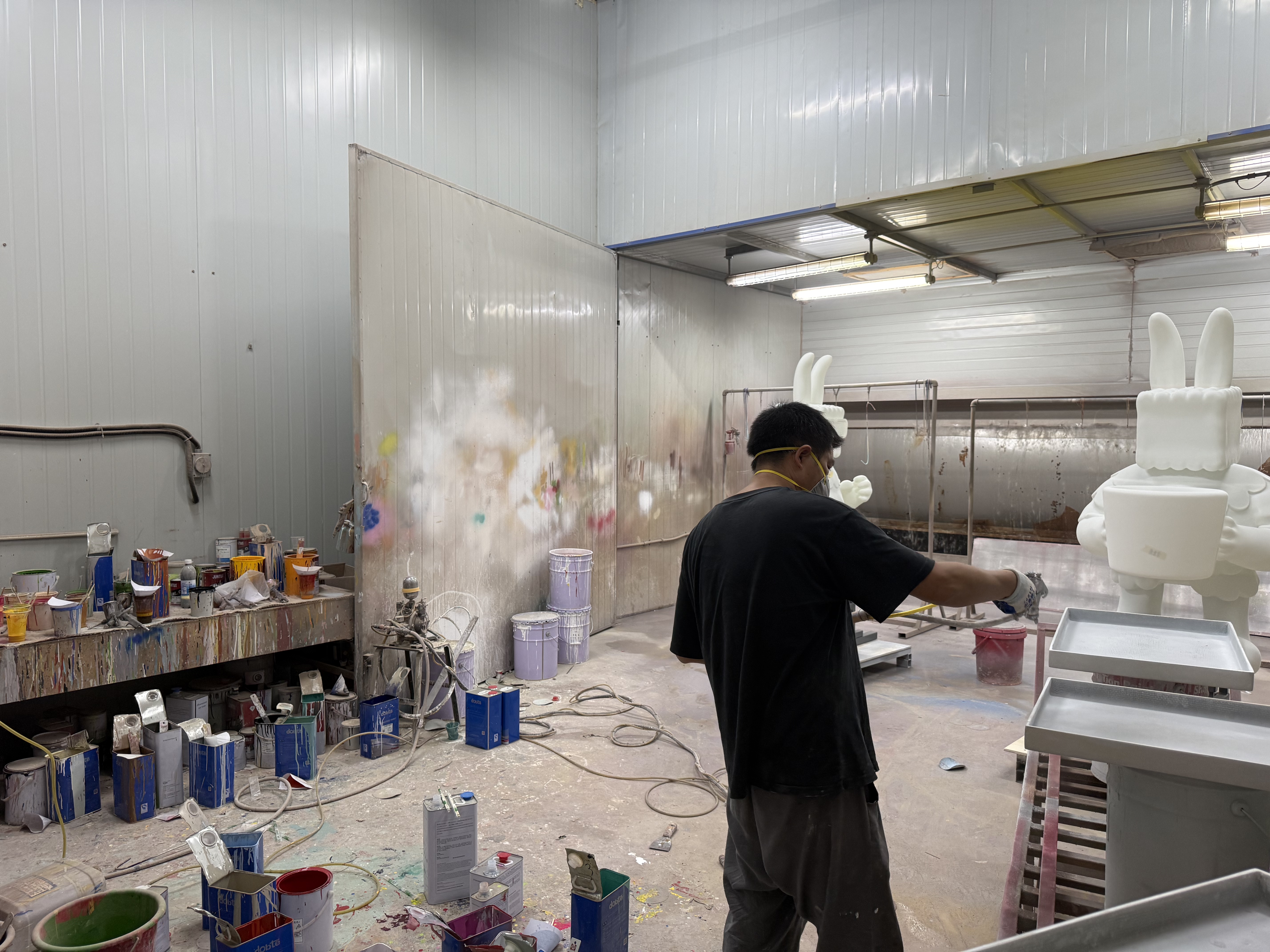 Spray-finishing a large fiberglass figure sculpture.